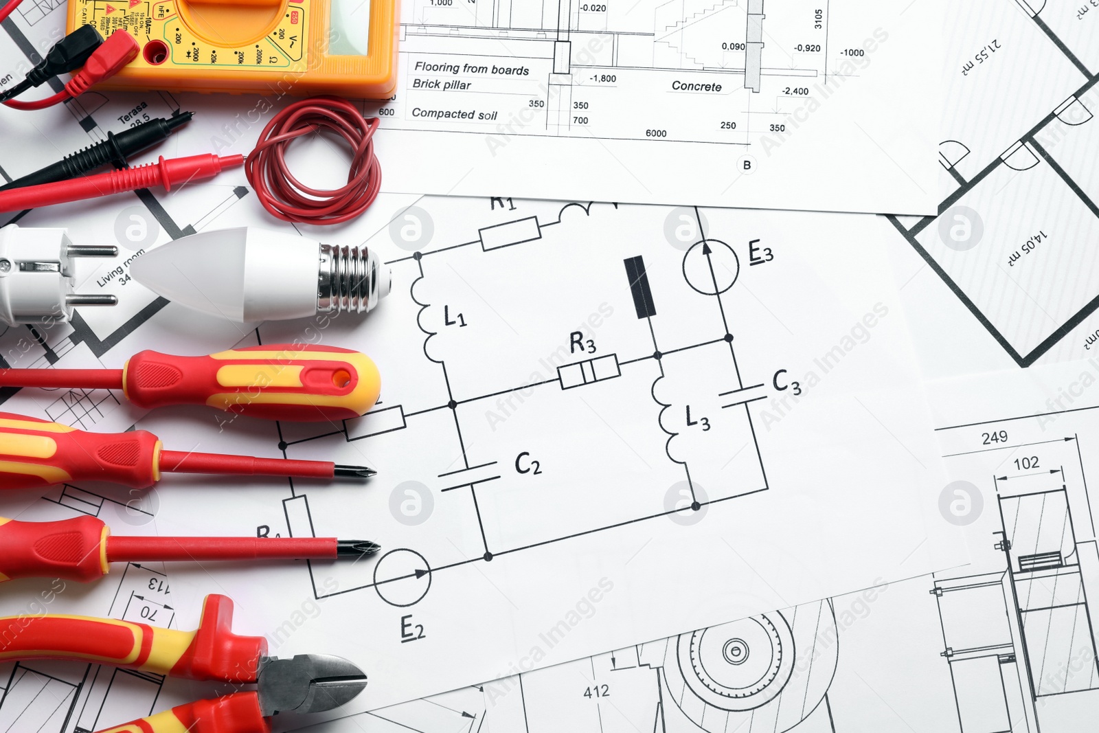 Photo of Set of electrician's tools and accessories on paper sheets, flat lay