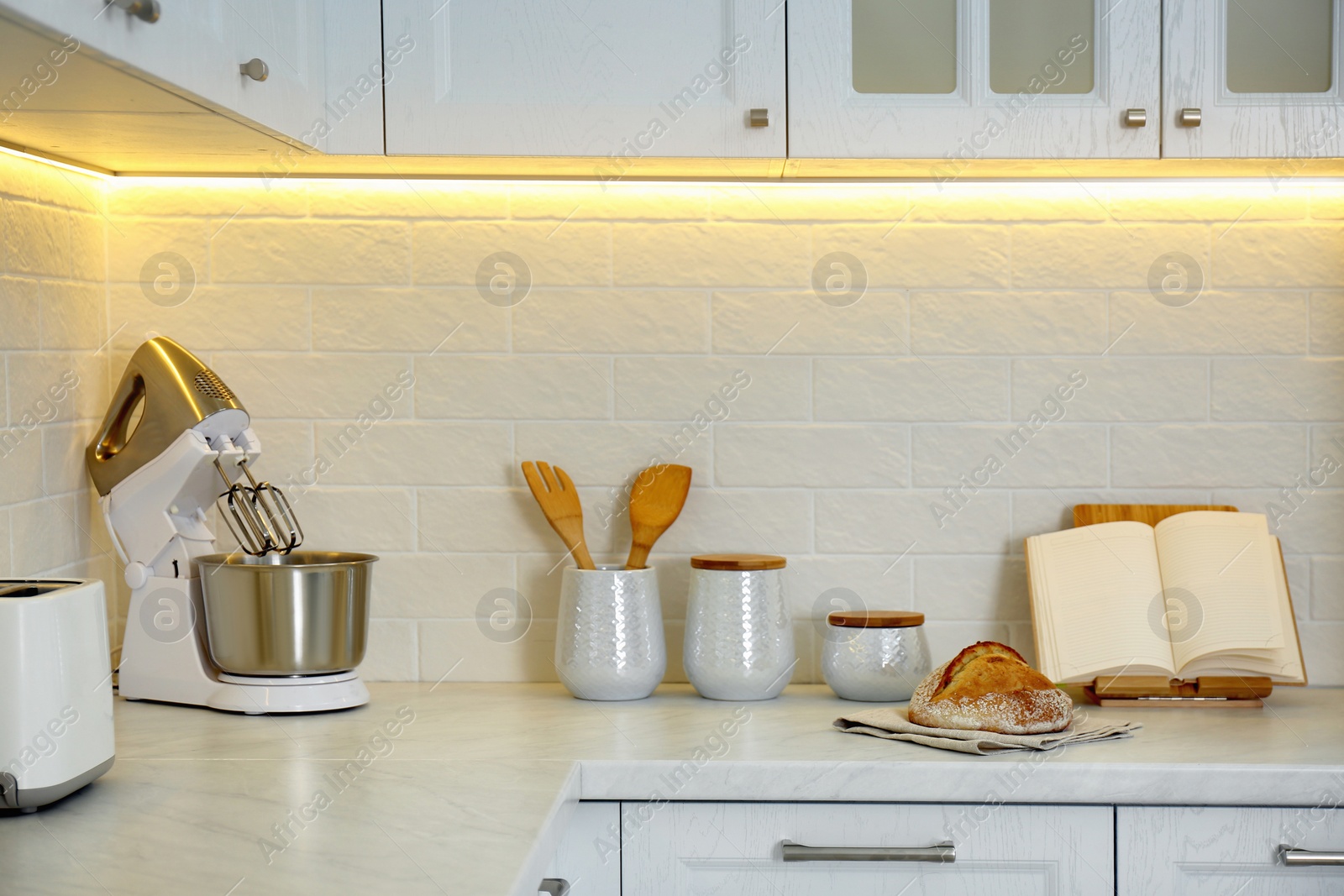 Photo of Countertop with modern food processor, cookbook and fresh bread in stylish kitchen