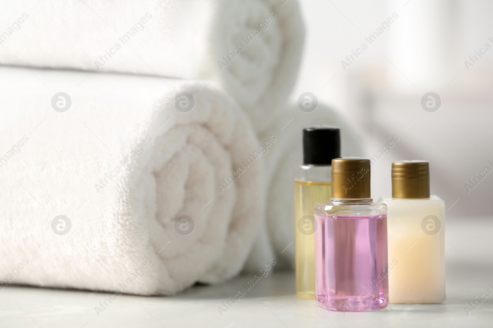 Photo of Mini bottles with cosmetic products and towels on table. Hotel amenities