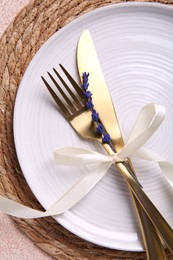 Photo of Cutlery, plate and preserved lavender flower on color textured table, top view