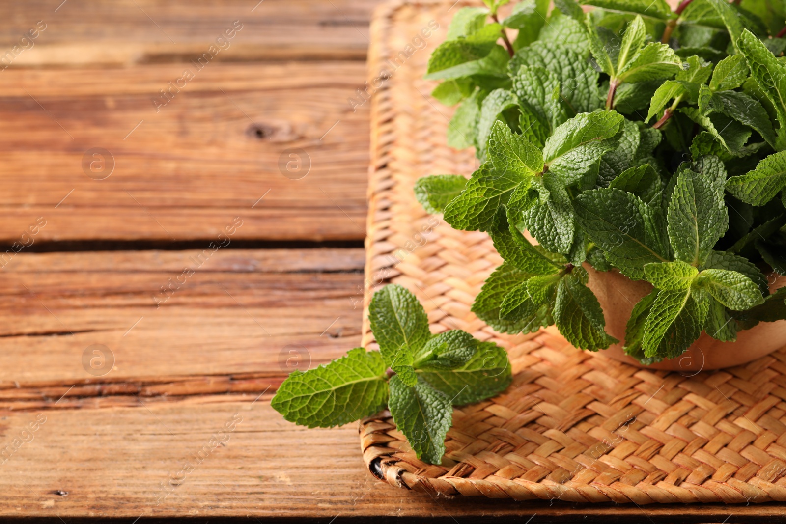 Photo of Bowl with fresh green mint leaves on wooden table, space for text