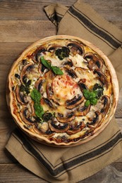 Delicious quiche with mushrooms and basil on wooden table, top view