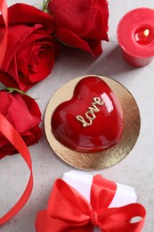 Photo of St. Valentine's Day. Delicious heart shaped cake, gift, roses and candle on light table, flat lay