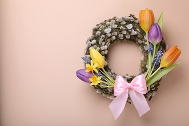 Photo of Willow wreath with different beautiful flowers and pink bow on beige background, top view. Space for text