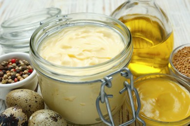 Photo of Delicious homemade mayonnaise, spices and ingredients on white wooden table, closeup