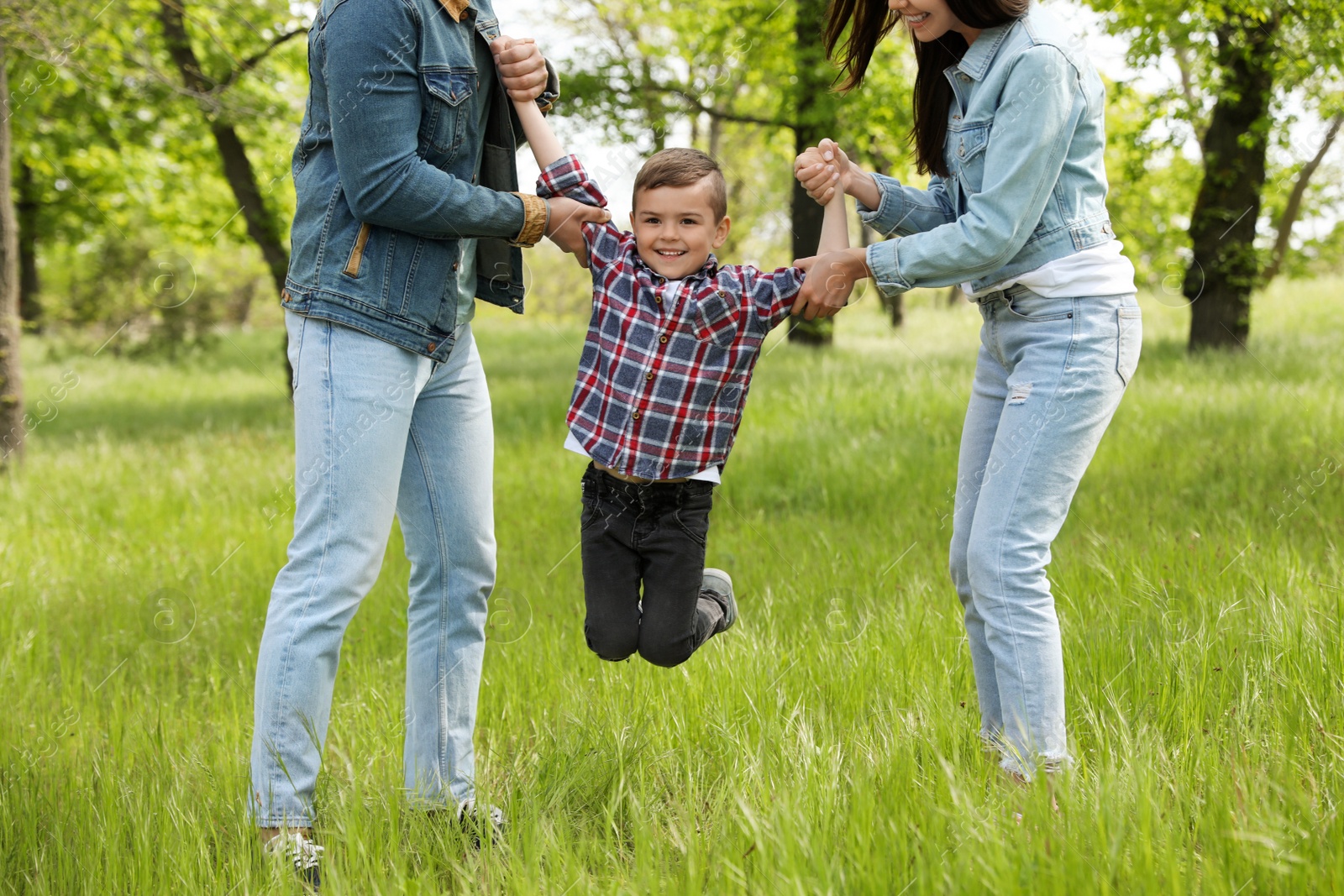 Photo of Cute little child having fun with his parents in park. Family weekend