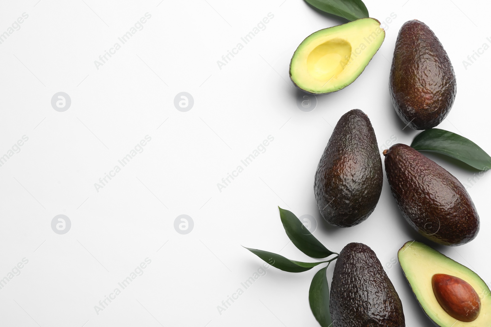 Photo of Whole and cut ripe avocadoes with green leaves on white background, top view