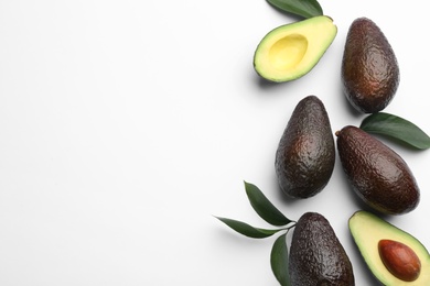 Photo of Whole and cut ripe avocadoes with green leaves on white background, top view