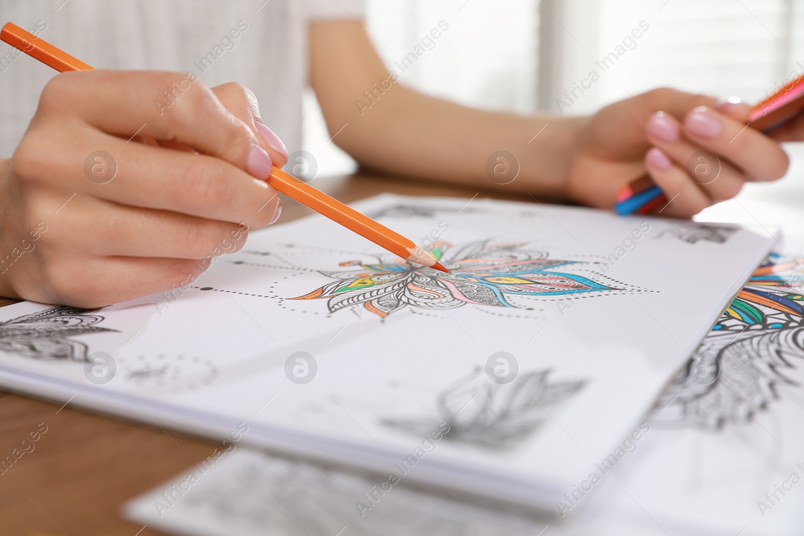 Photo of Young woman coloring antistress page at table indoors, closeup