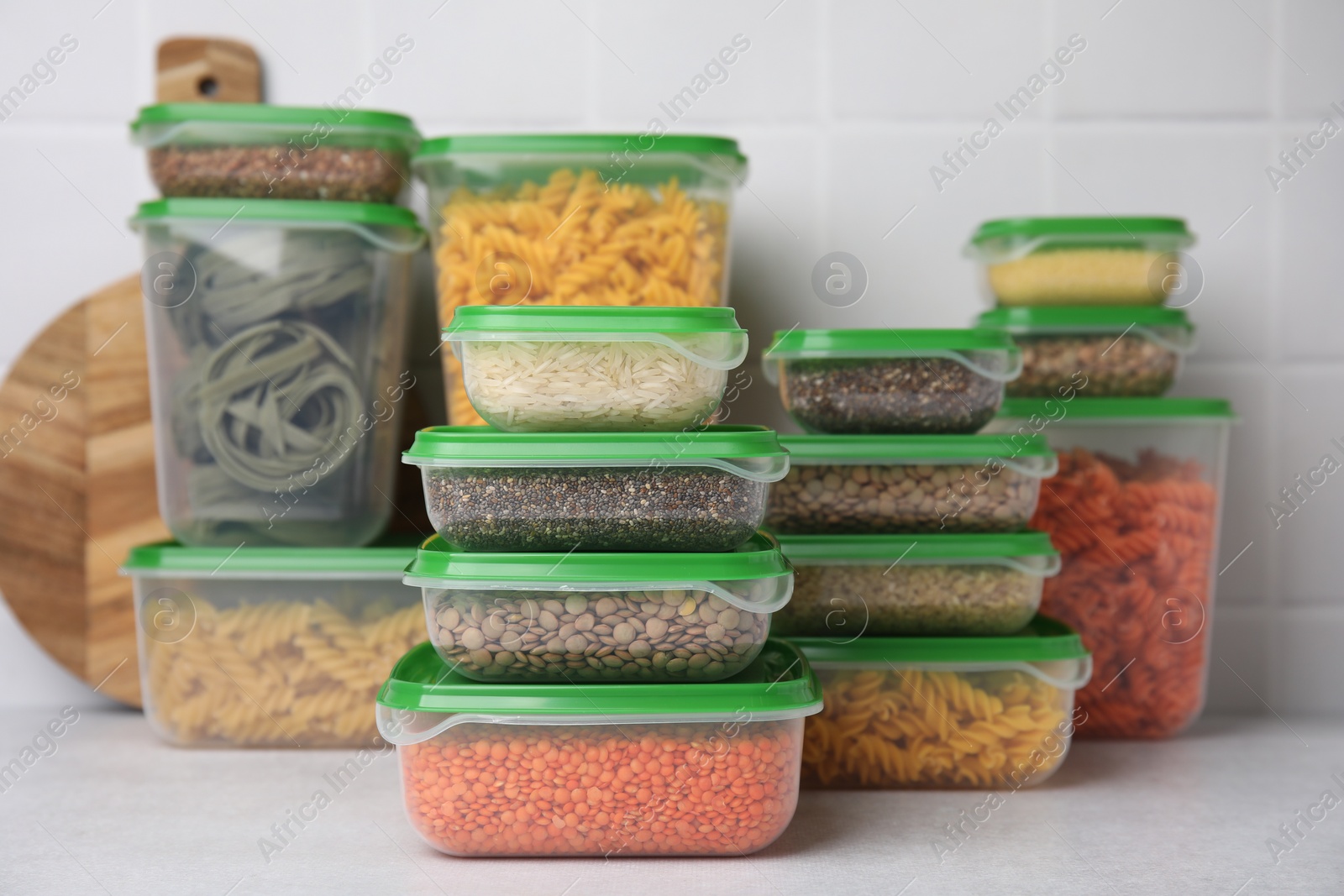 Photo of Plastic containers filled with food products on white table near tiled wall