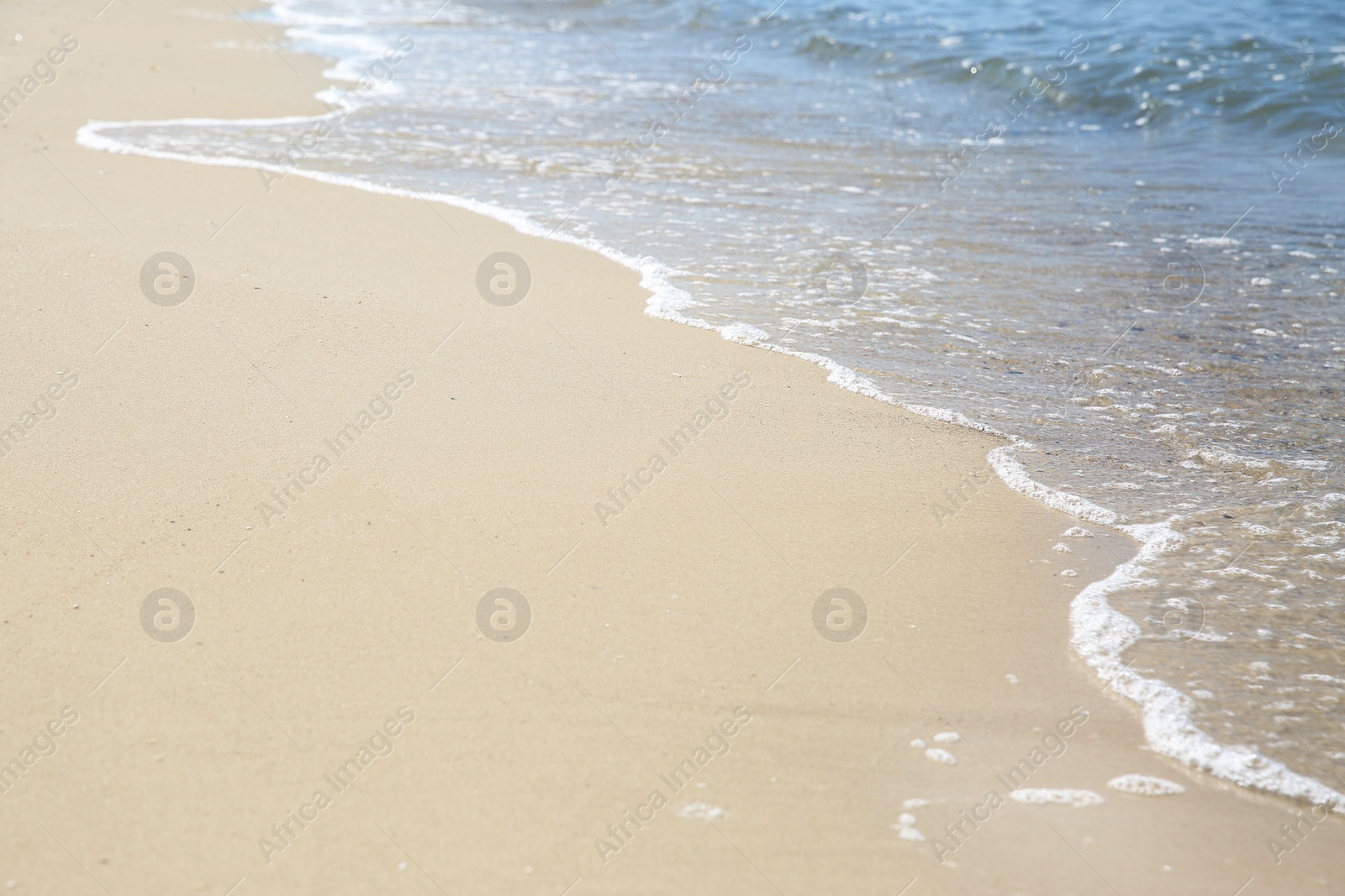 Photo of Beautiful sea waves on sandy beach, closeup