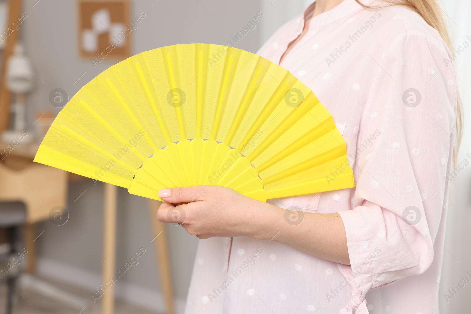 Photo of Woman with yellow hand fan at home, closeup