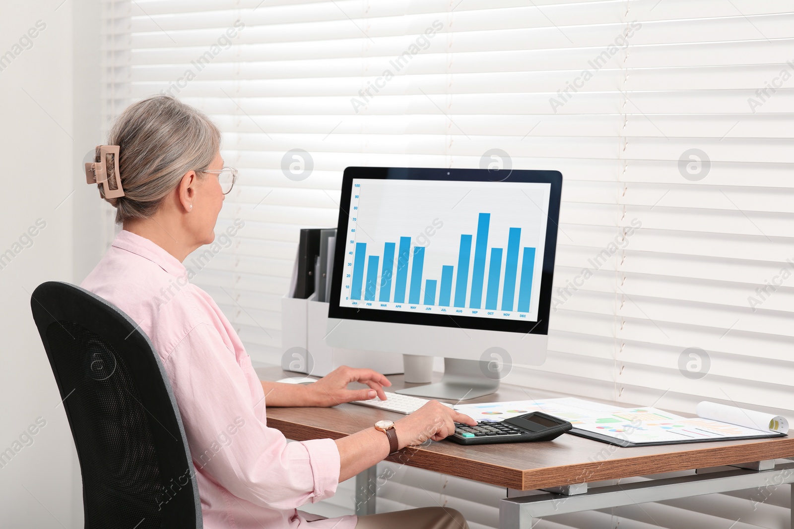 Photo of Senior accountant working at wooden desk in office