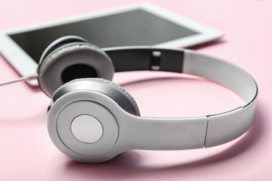 Stylish headphones and tablet on color background