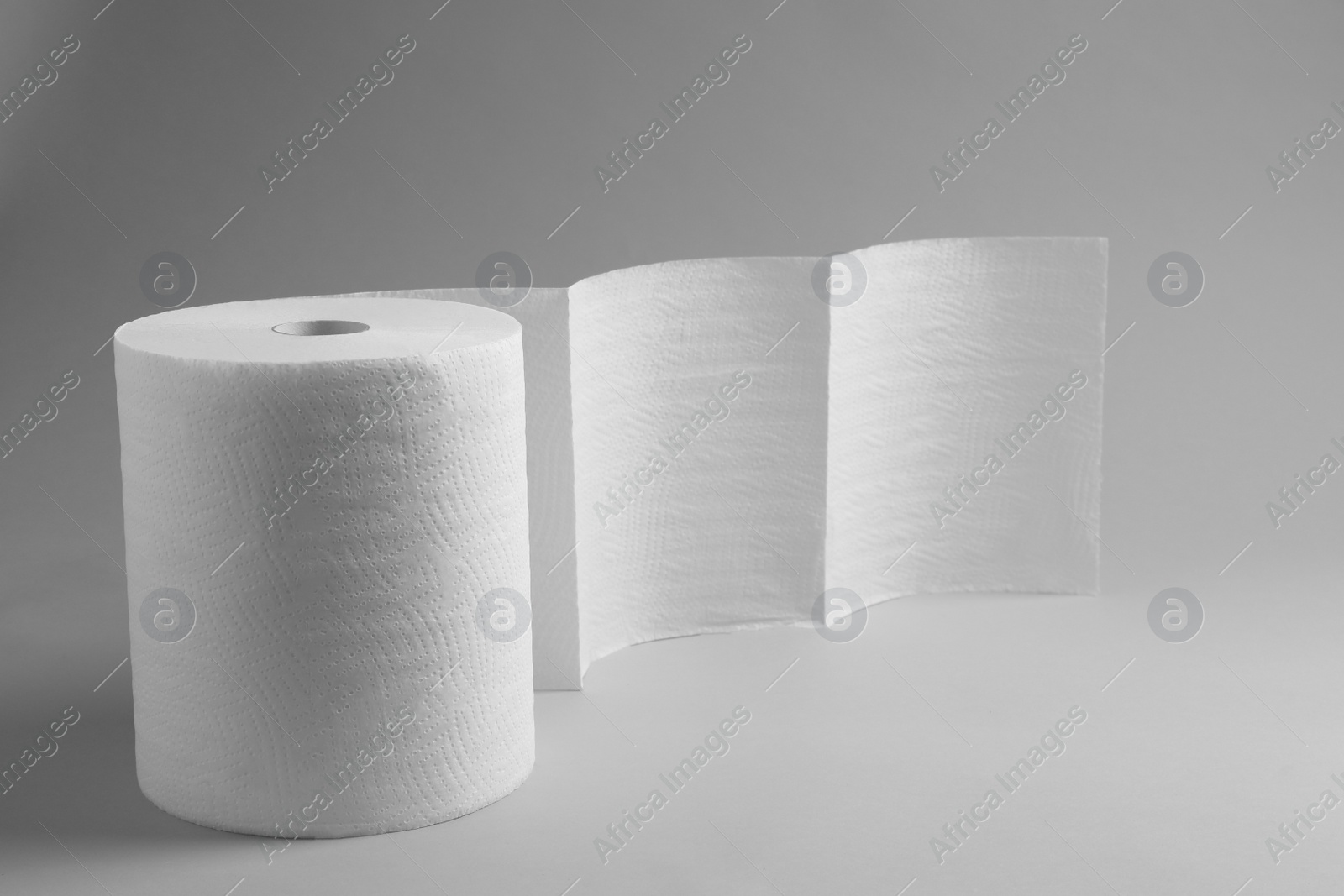 Photo of Roll of white paper towels on grey background. Space for text