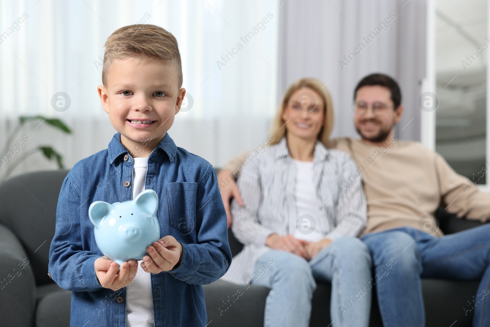 Photo of Family budget. Little boy with piggy bank and his parents at home, selective focus