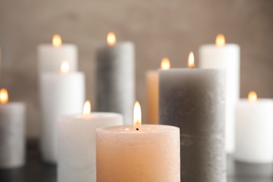 Photo of Burning candles on table against color background, closeup