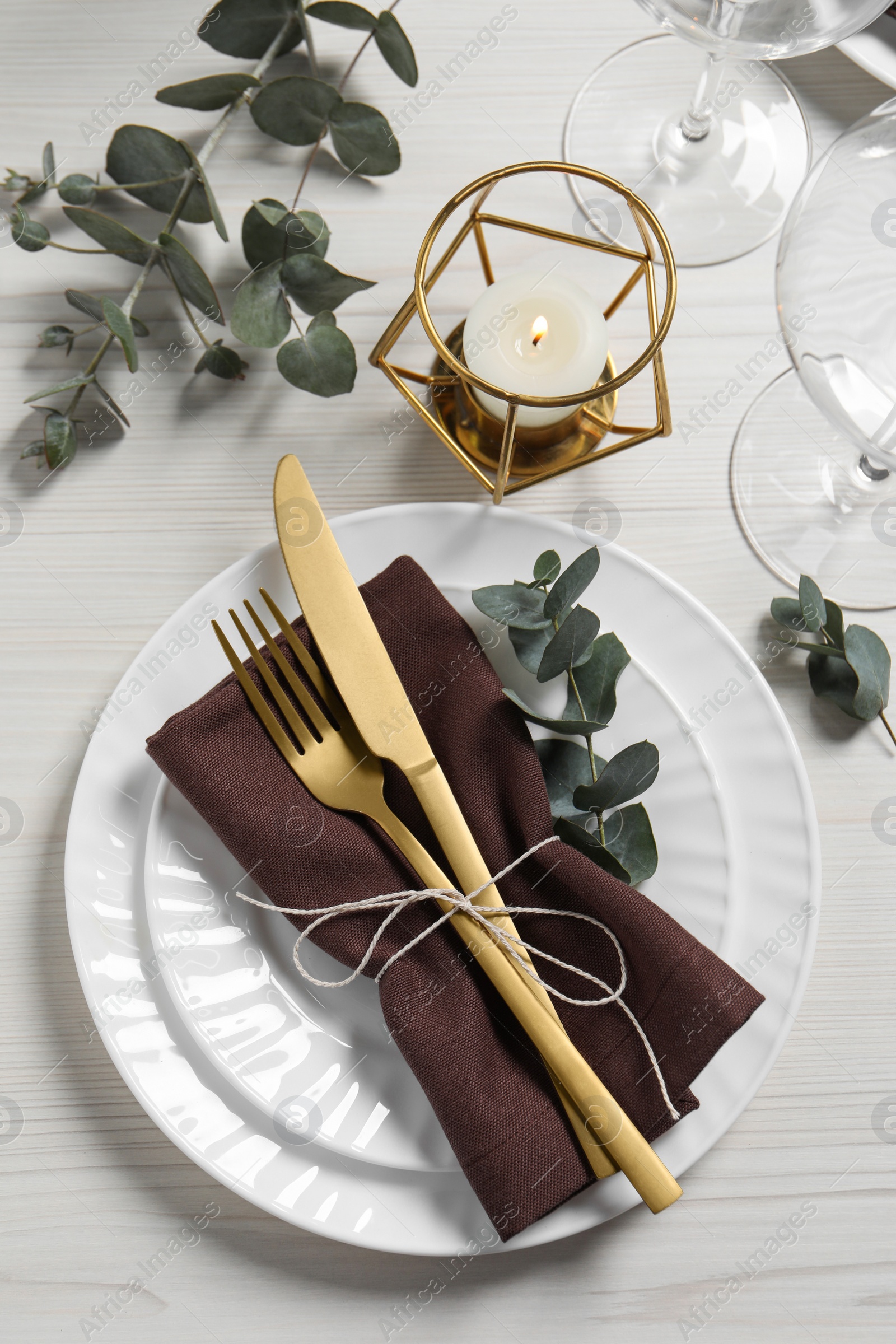 Photo of Stylish setting with cutlery and eucalyptus leaves on white wooden table, flat lay