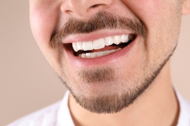 Photo of Young man with healthy teeth smiling on color background, closeup