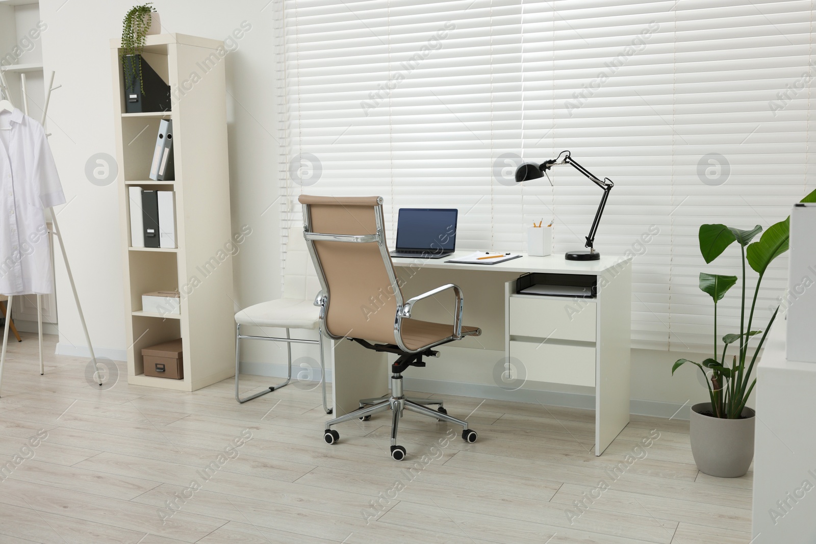 Photo of Doctor's workplace. Chair, laptop and clipboard on white table in clinic