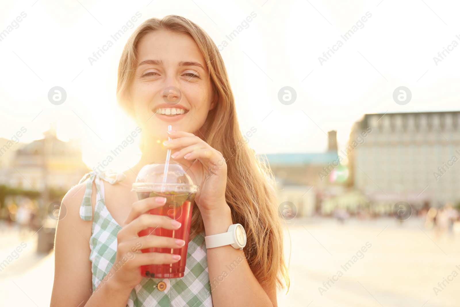 Photo of Young woman with refreshing drink on city street. Space for text