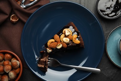 Piece of tasty homemade chocolate cake with nuts served on black table, flat lay