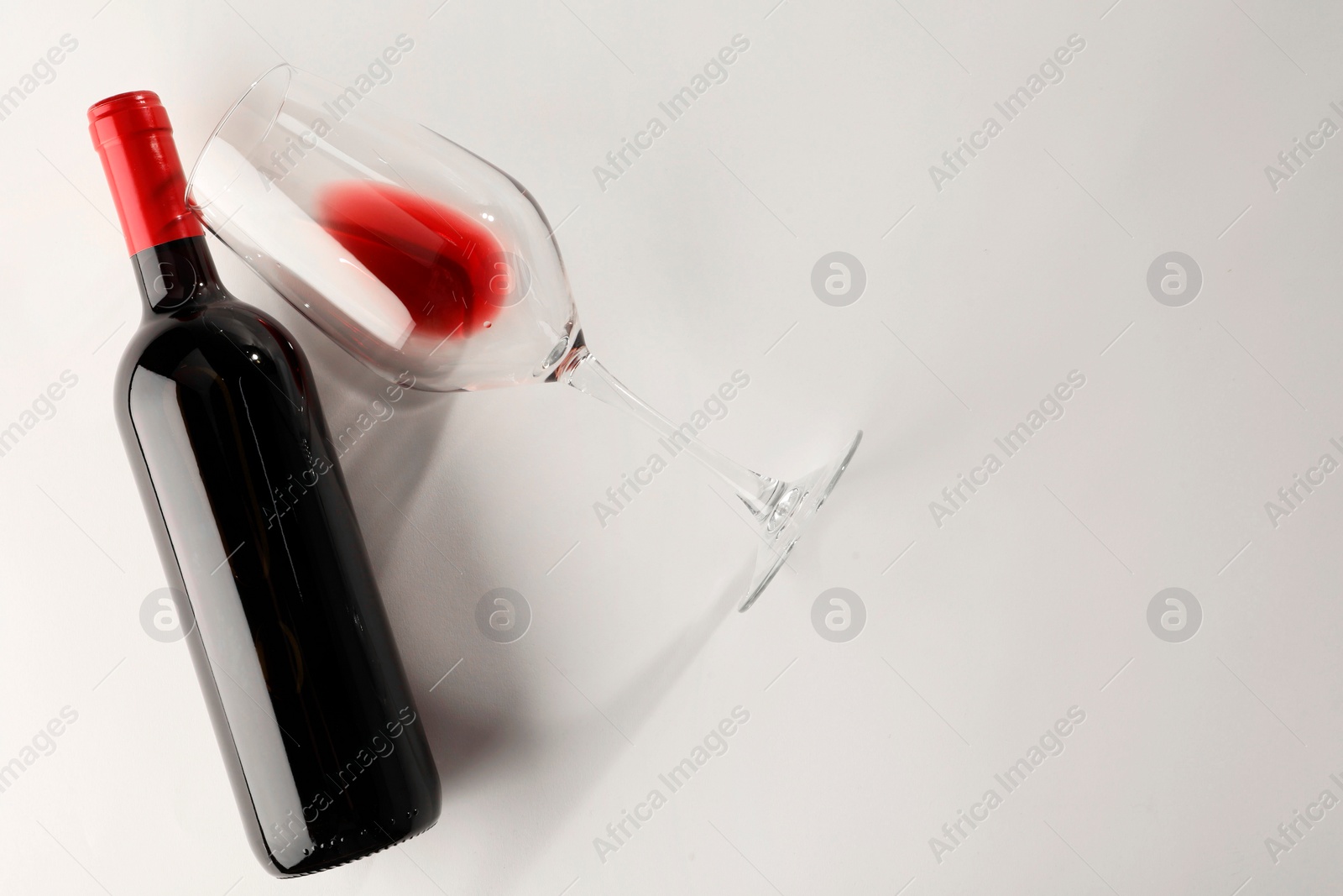 Photo of Bottle of expensive red wine and wineglass on white background, top view. Space for text