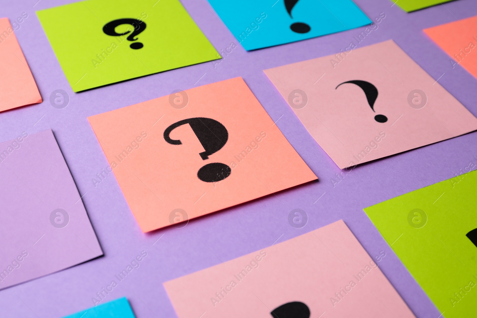 Photo of Paper cards with question marks on violet background, closeup