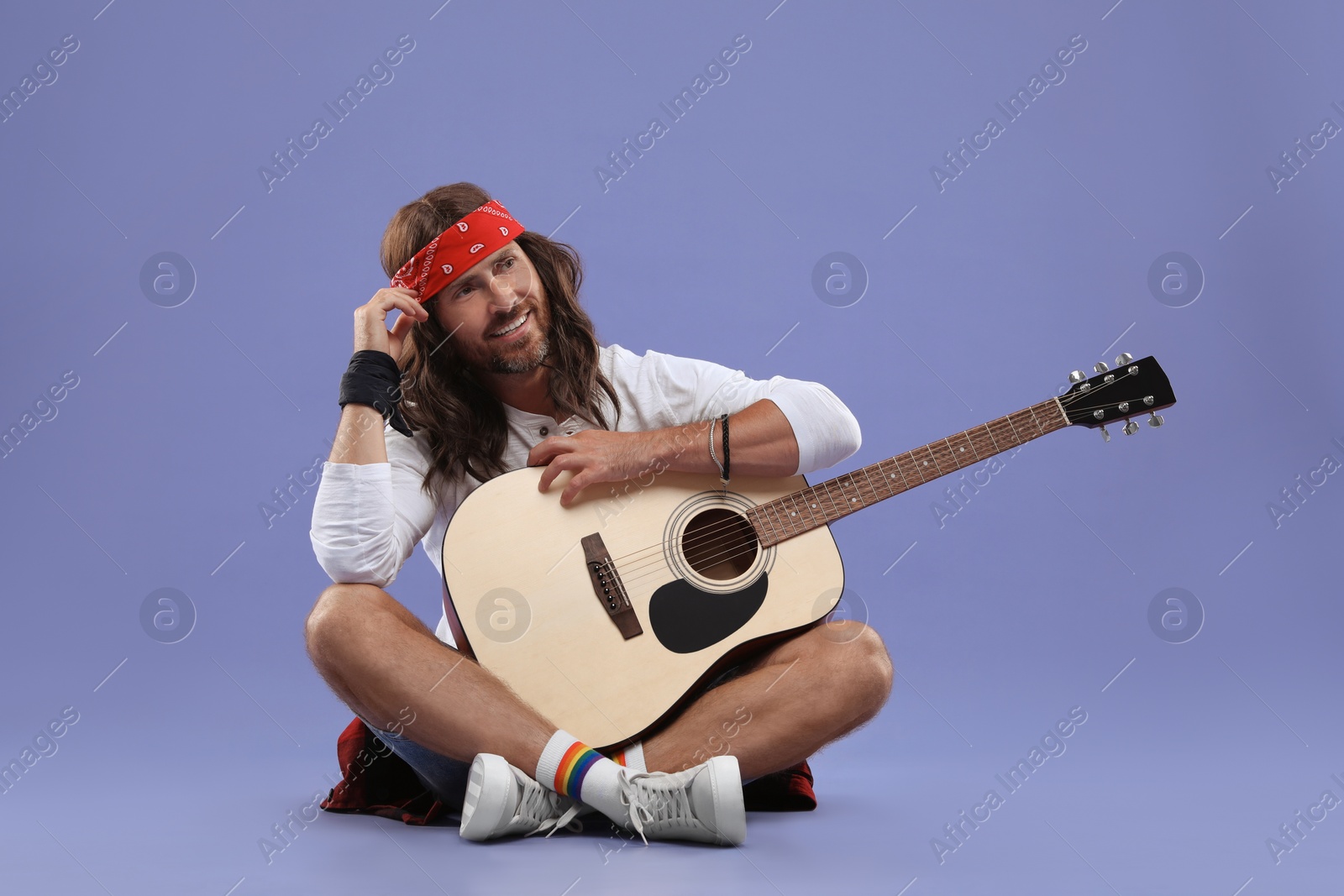 Photo of Stylish hippie man with guitar on violet background