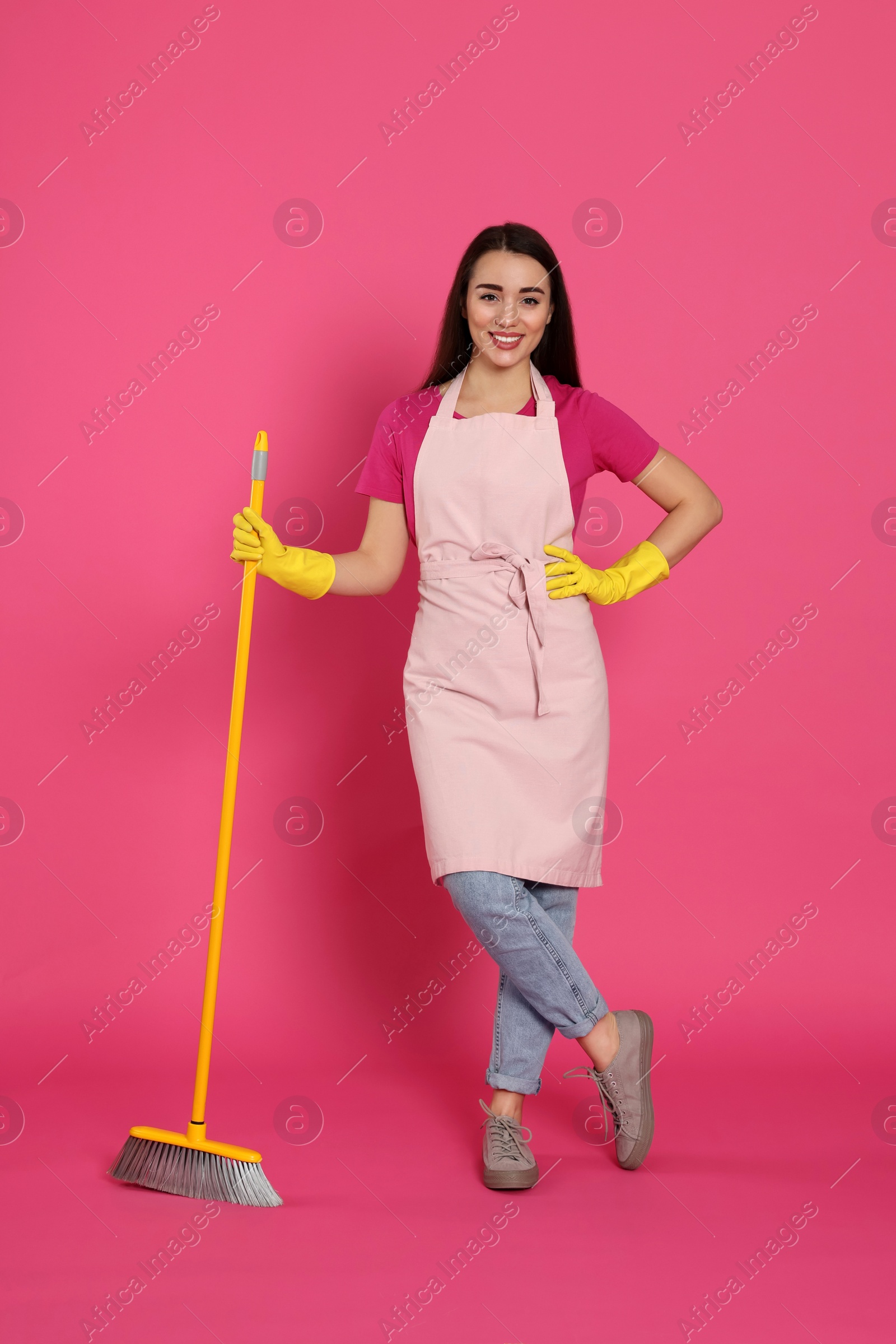 Photo of Beautiful young woman with broom on pink background