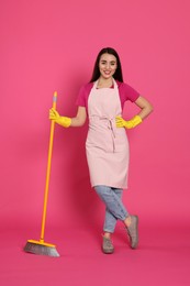 Beautiful young woman with broom on pink background