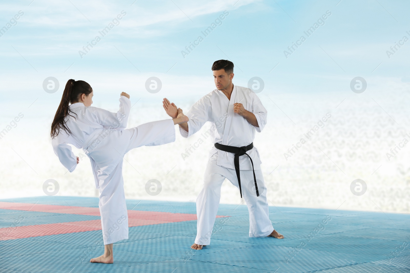 Photo of Girl practicing karate with coach on tatami outdoors