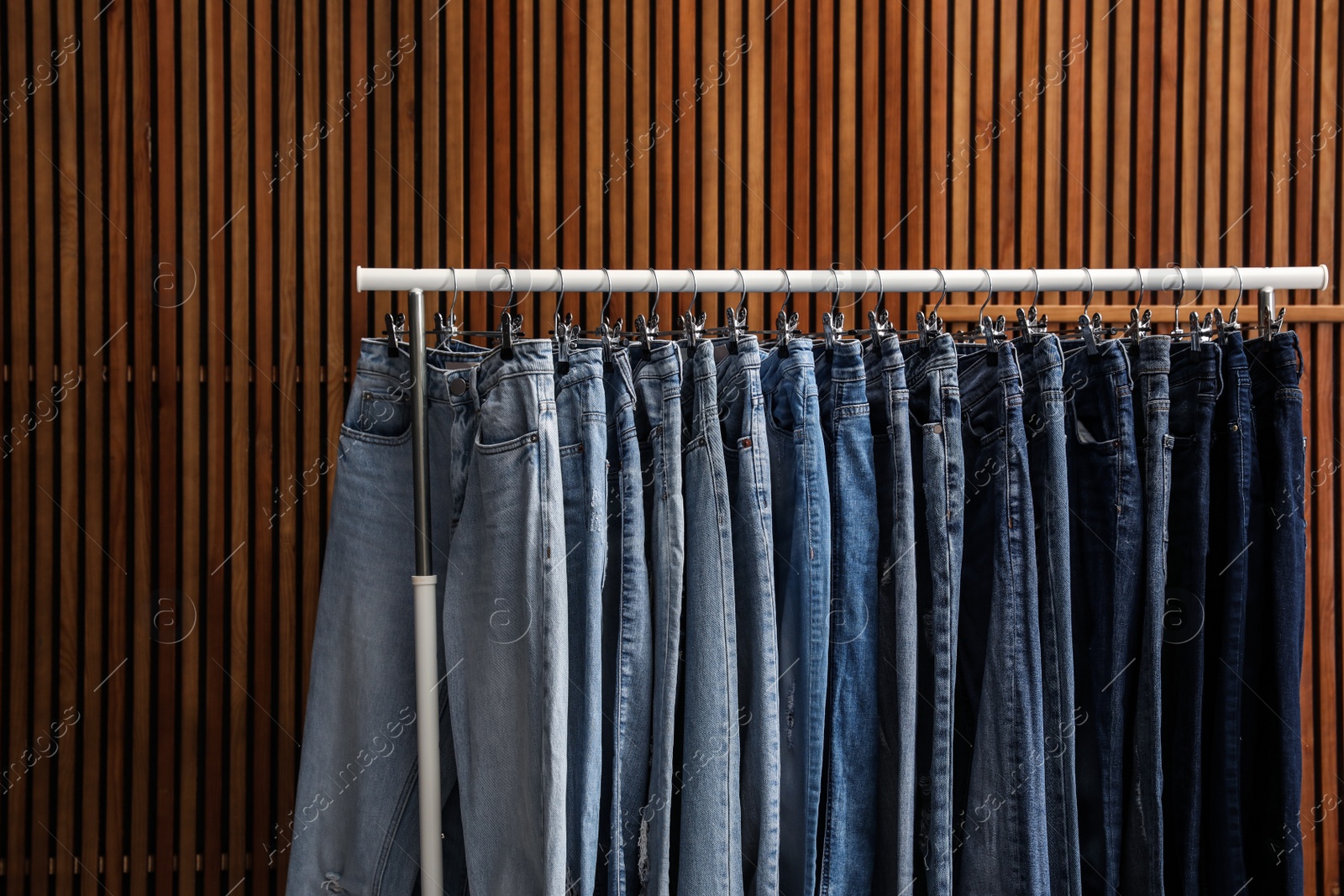 Photo of Rack with different jeans on wooden background