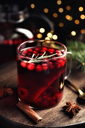 Photo of Tasty hot cranberry tea with rosemary and cinnamon on wooden table, closeup