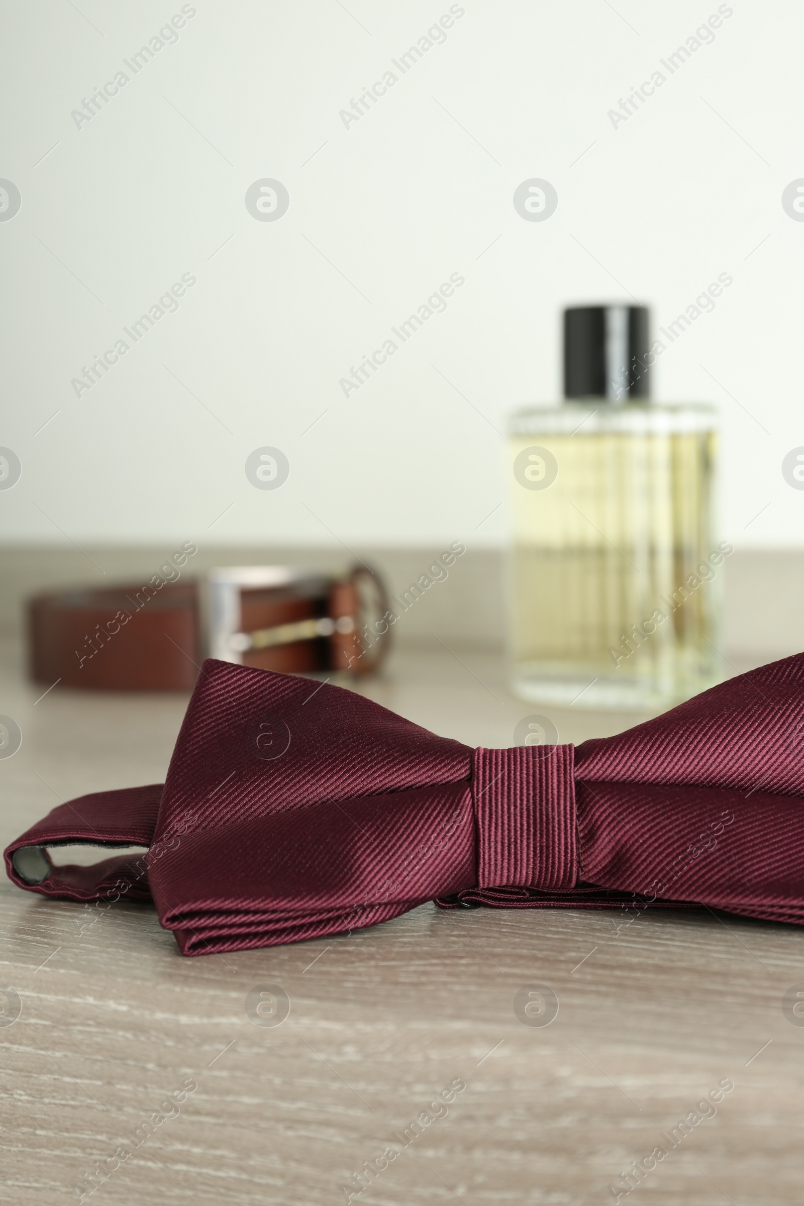 Photo of Stylish burgundy bow tie on wooden table, closeup