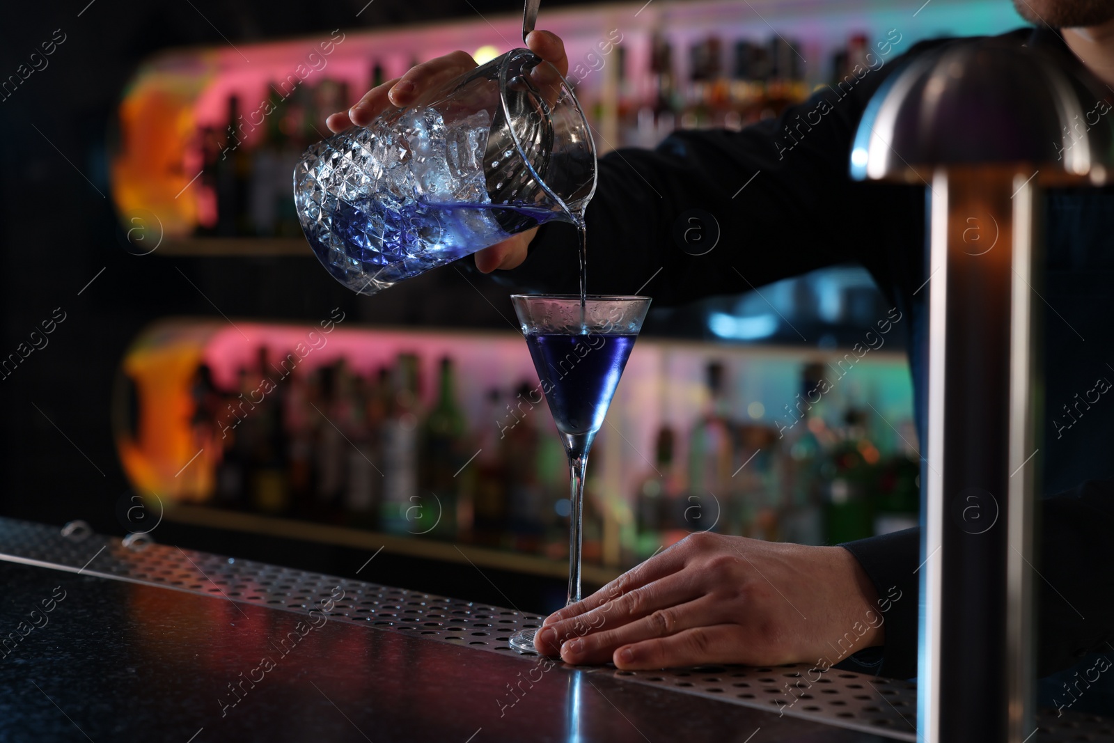 Photo of Bartender making fresh alcoholic cocktail at counter in bar, closeup