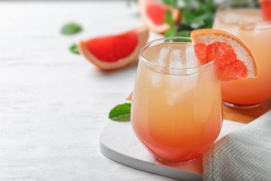 Photo of Glass of delicious cocktail decorated with grapefruit on white wooden table, closeup. Space for text