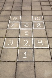 Hopscotch drawn with white chalk on street tiles outdoors