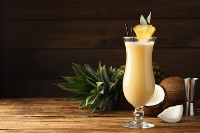 Photo of Tasty Pina Colada cocktail and ingredients on wooden table, space for text