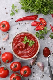 Photo of Flat lay composition with organic ketchup in bowl on grey textured table. Tomato sauce