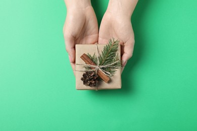 Photo of Christmas present. Woman holding beautifully wrapped gift box on green background, top view
