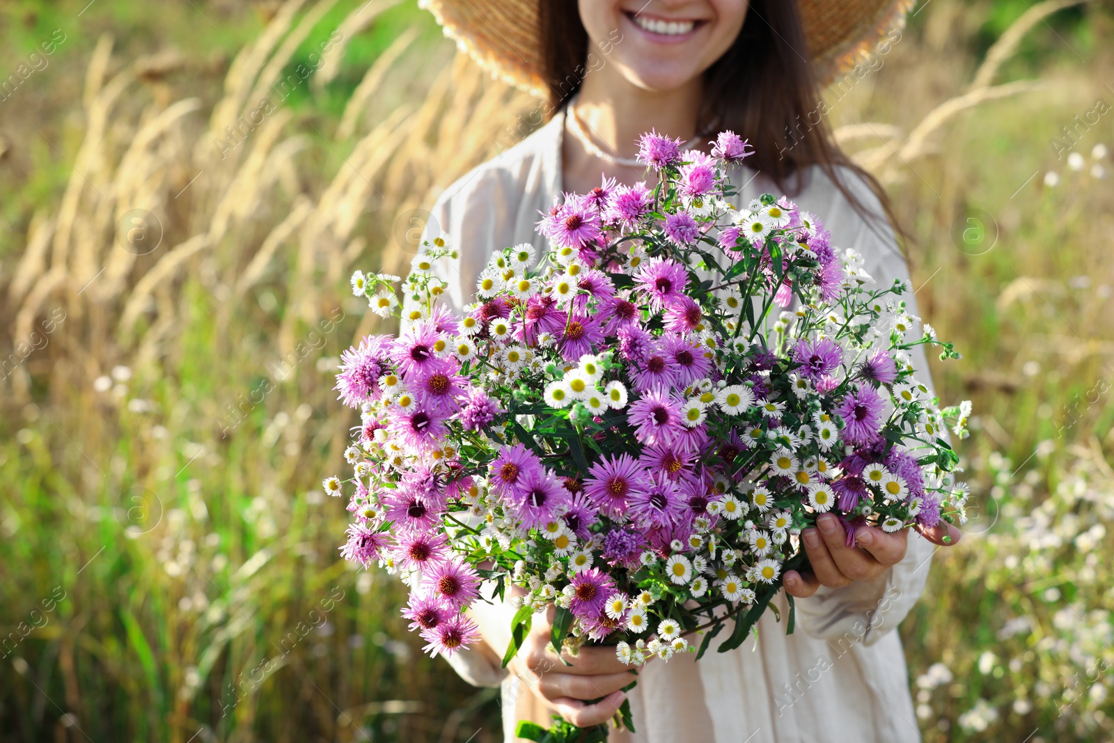 Photo of Woman holding bouquet of beautiful wild flowers outdoors, closeup