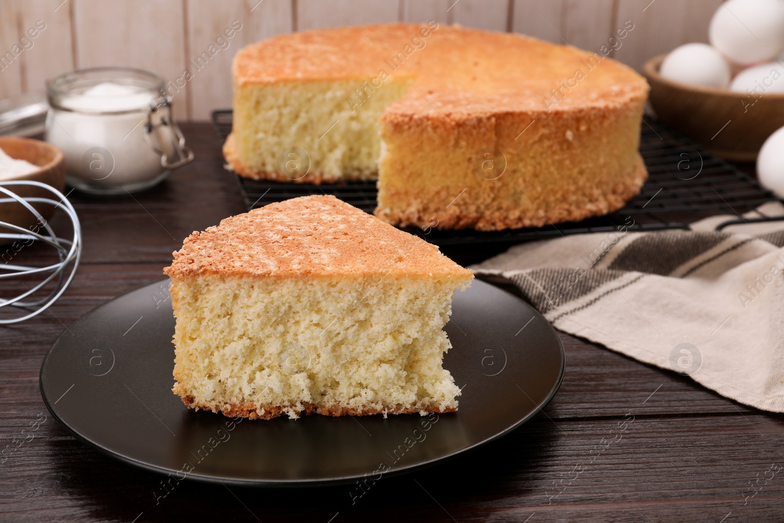 Photo of Tasty sponge cake and ingredients on wooden table