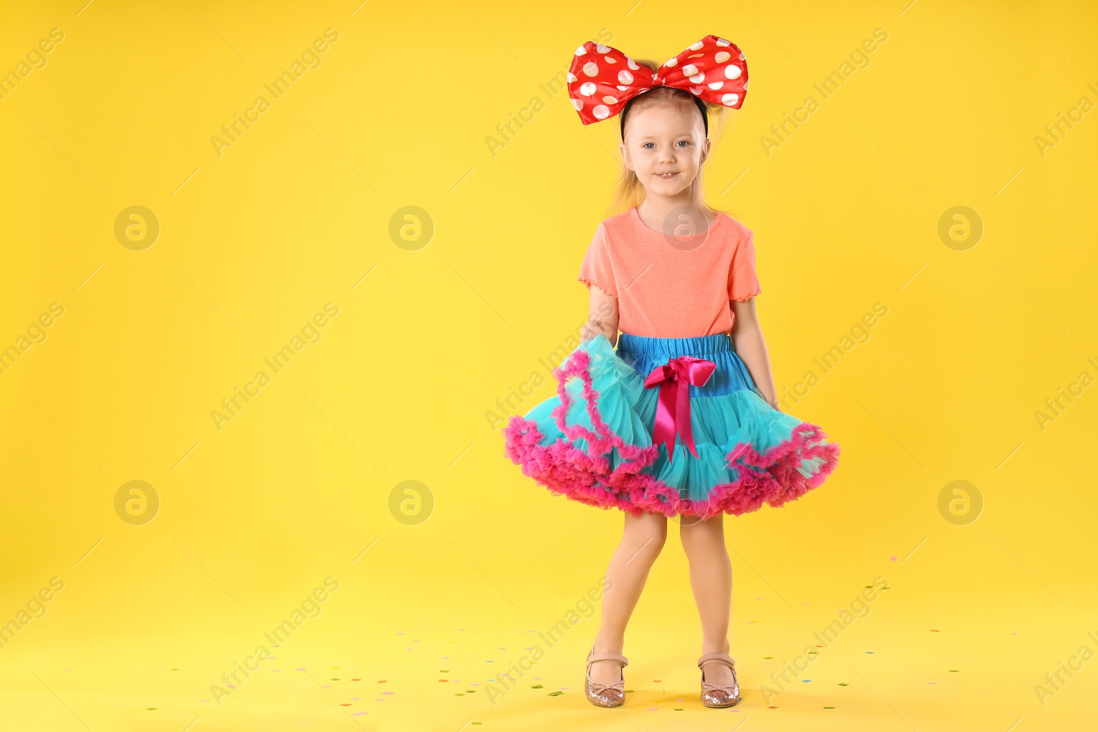 Photo of Little girl in cute costume on yellow background, space for text. April fool's day
