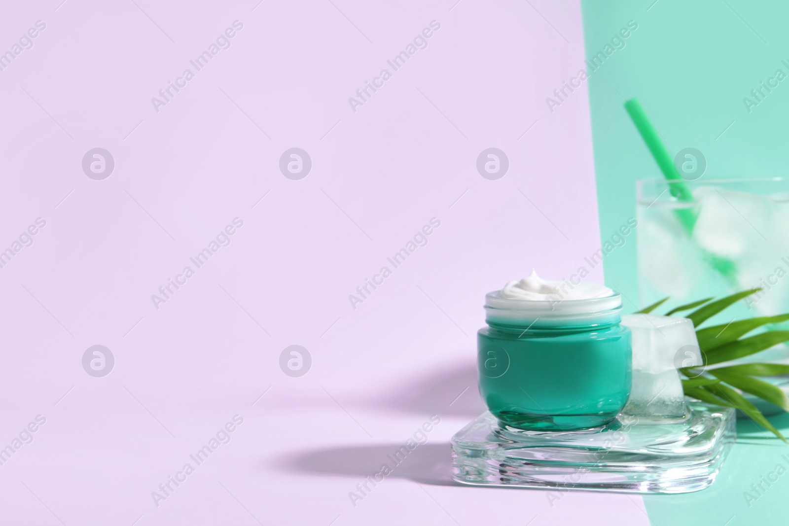 Photo of Cream with ice, green leaf and glass of cold drink on color background. Space for text