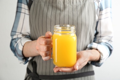 Photo of Woman holding mason jar of immunity boosting drink in hands, closeup