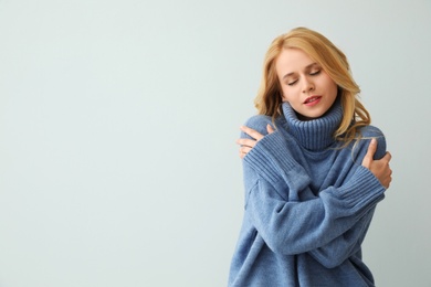 Photo of Beautiful young woman wearing warm blue sweater on light background. Space for text