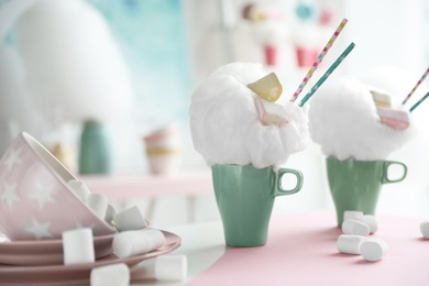 Photo of Cups of tasty cotton candy dessert and marshmallow on table, space for text