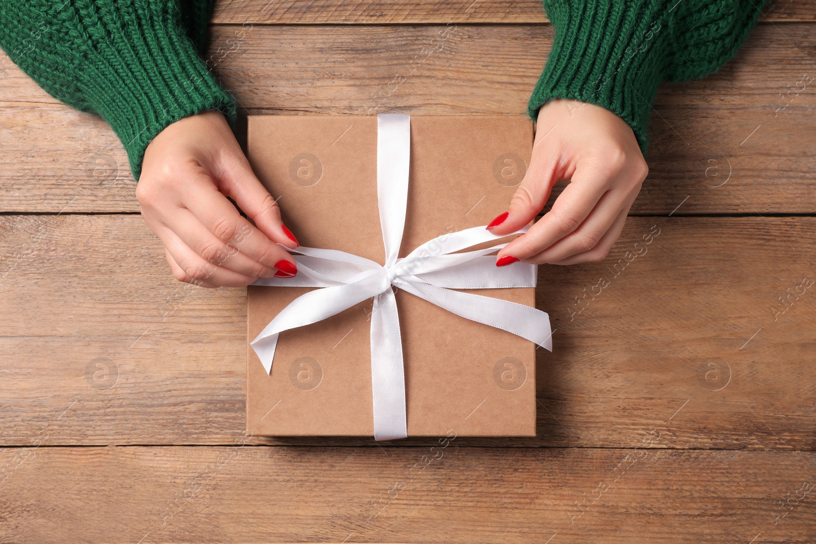 Photo of Christmas present. Woman with gift box at wooden table, top view