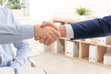 Photo of Lawyer handshaking with client in office, closeup